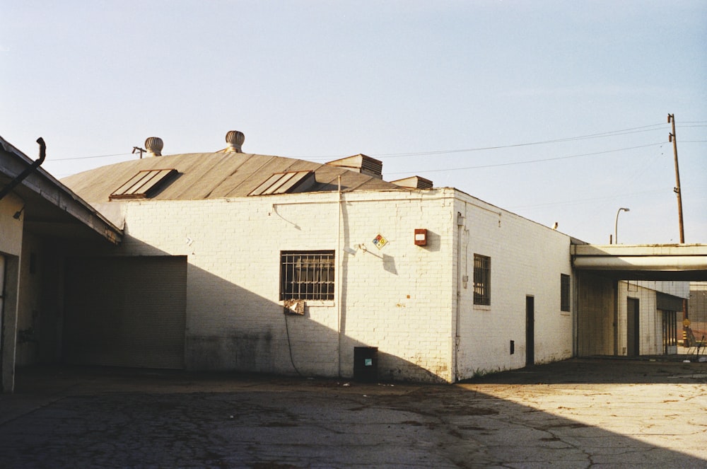 a white building with a metal roof next to a parking lot