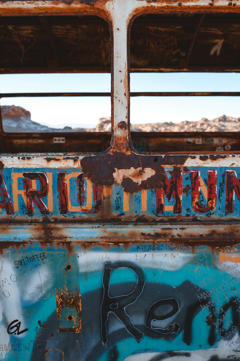 a rusted out bus with graffiti on it