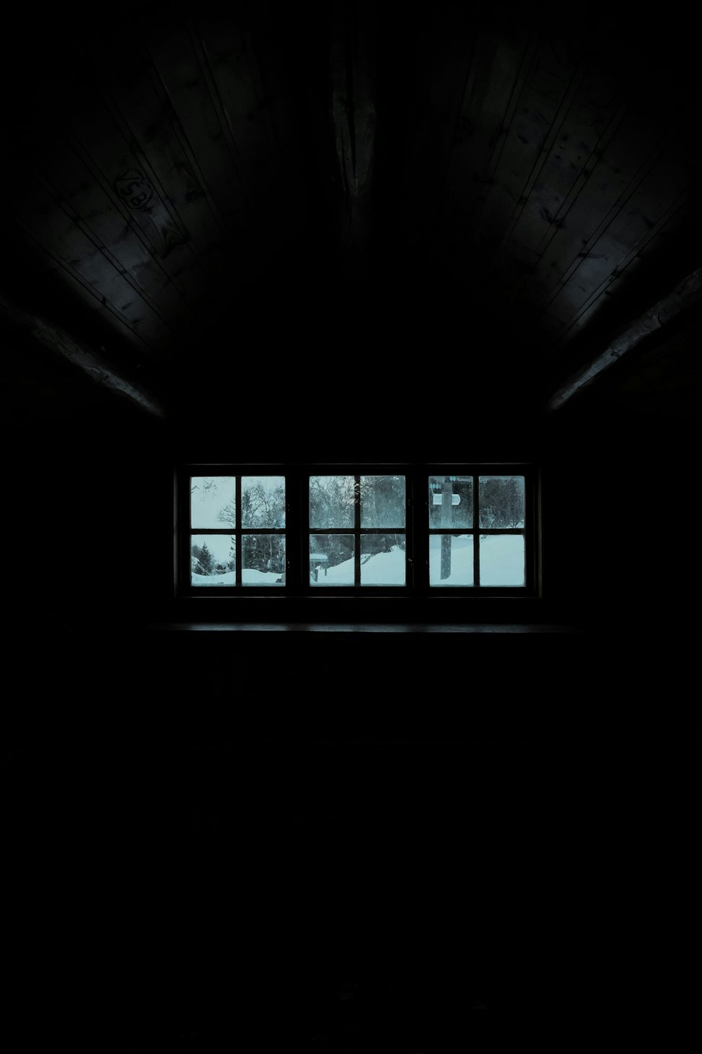 a window in a dark room with snow outside