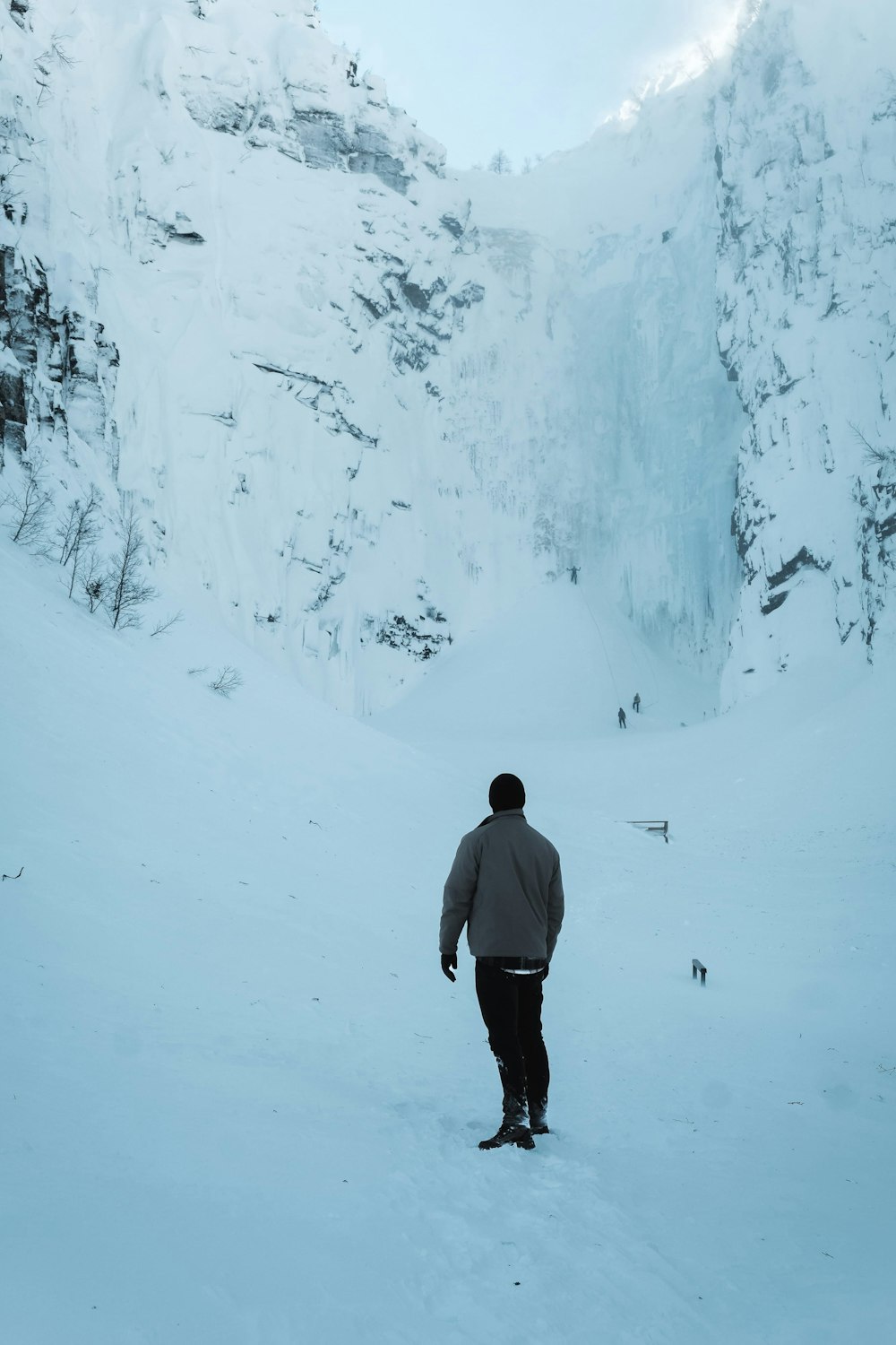 a man standing in the snow in front of a mountain