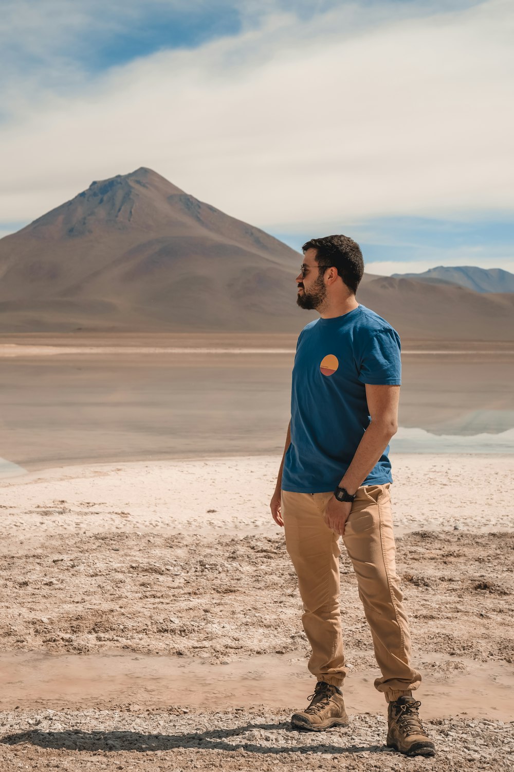 a man standing in the desert with a mountain in the background