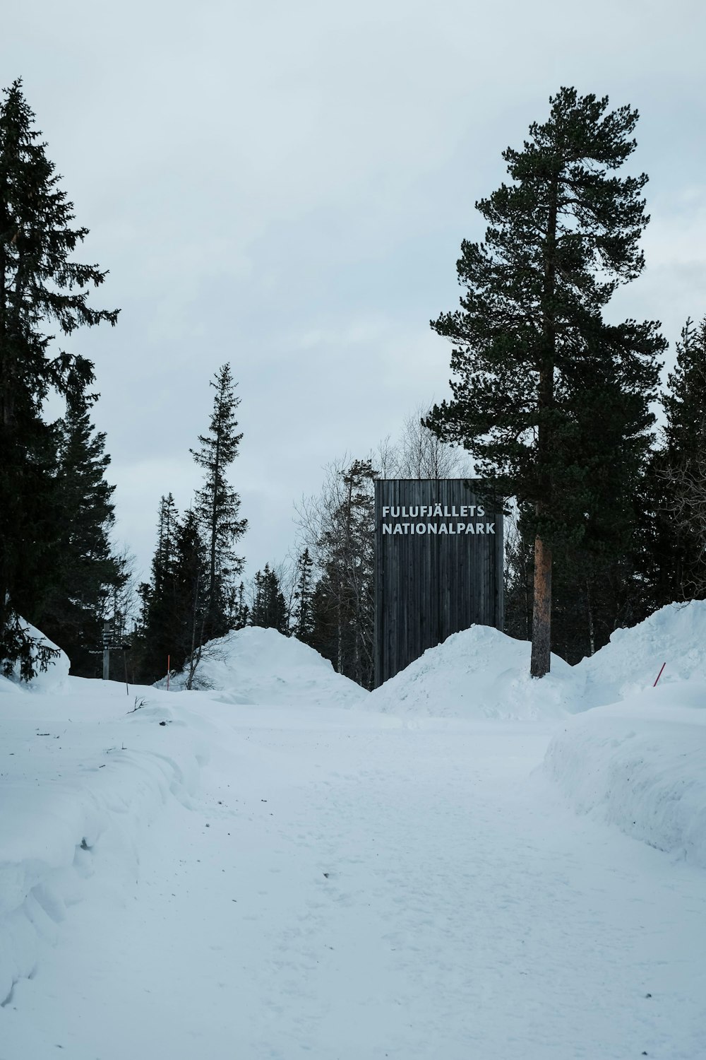 a snow covered road with a sign in the background