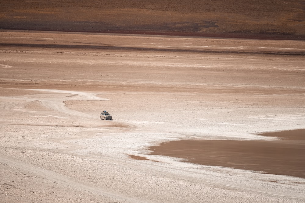 a car driving on a dirt road near a body of water