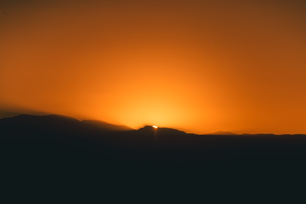 the sun is setting over a mountain range