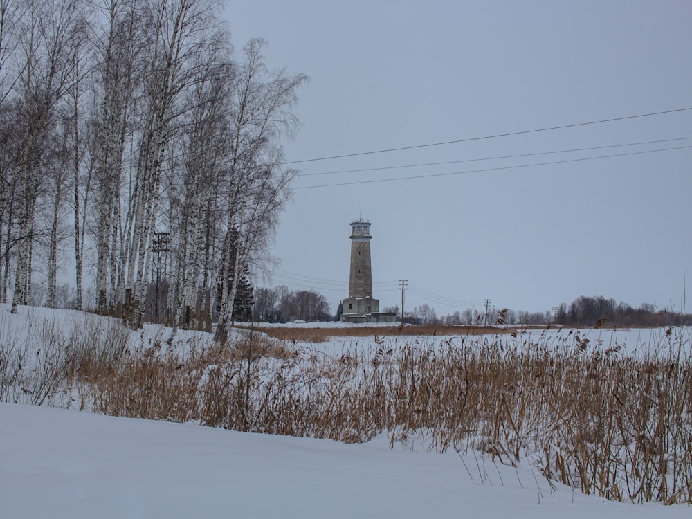 a snow covered field with a light tower in the background