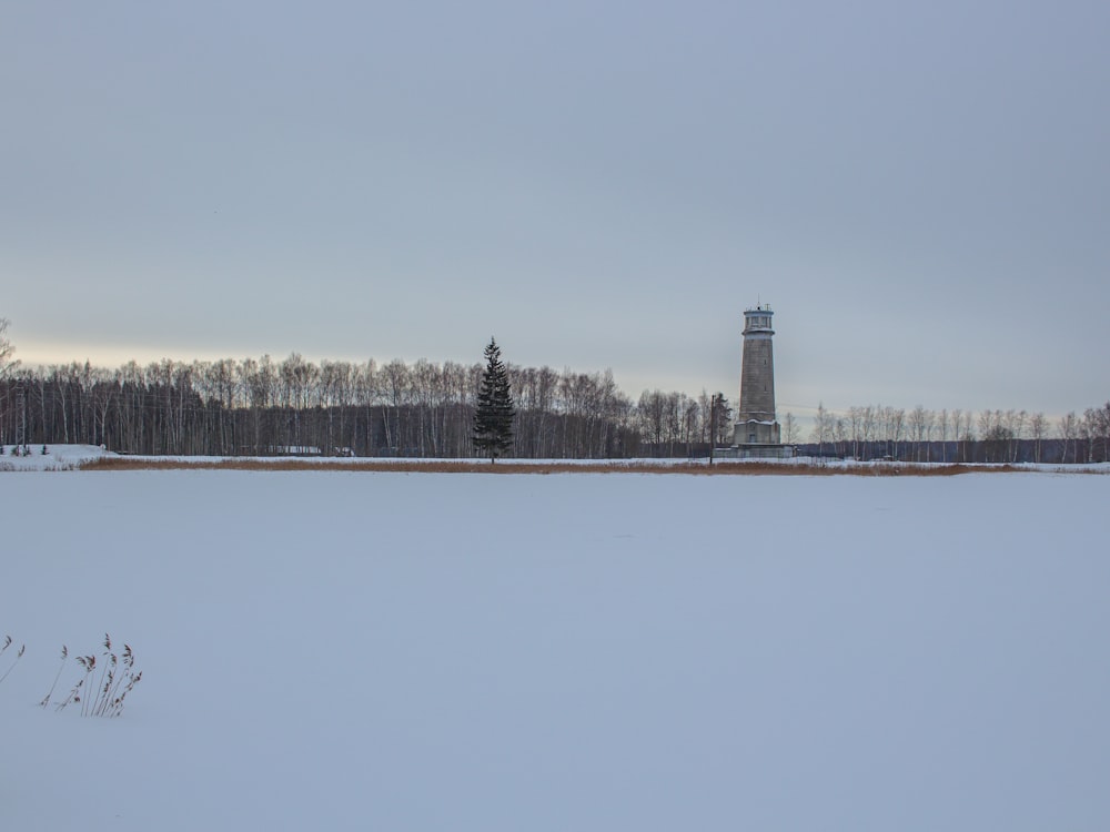 a snowy field with a light house in the distance