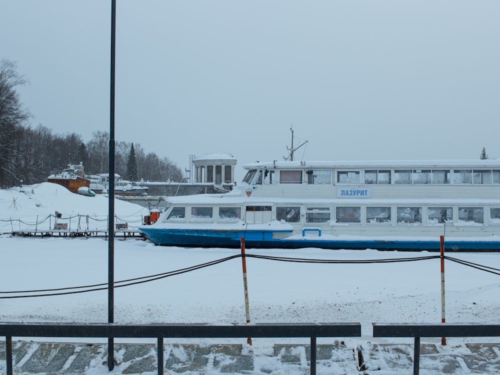 a white and blue boat sitting in the snow