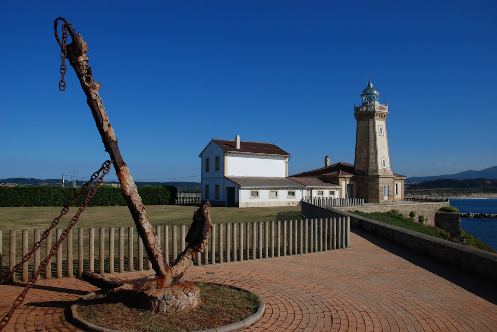 a white lighthouse and a wooden fence with a tree in the foreground