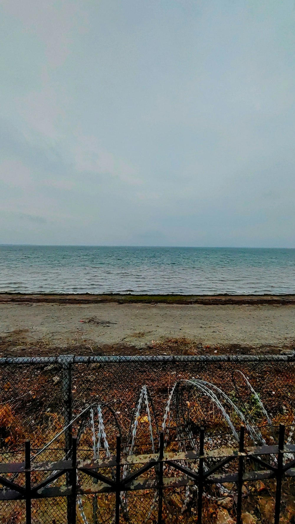 a view of the ocean from behind a fence