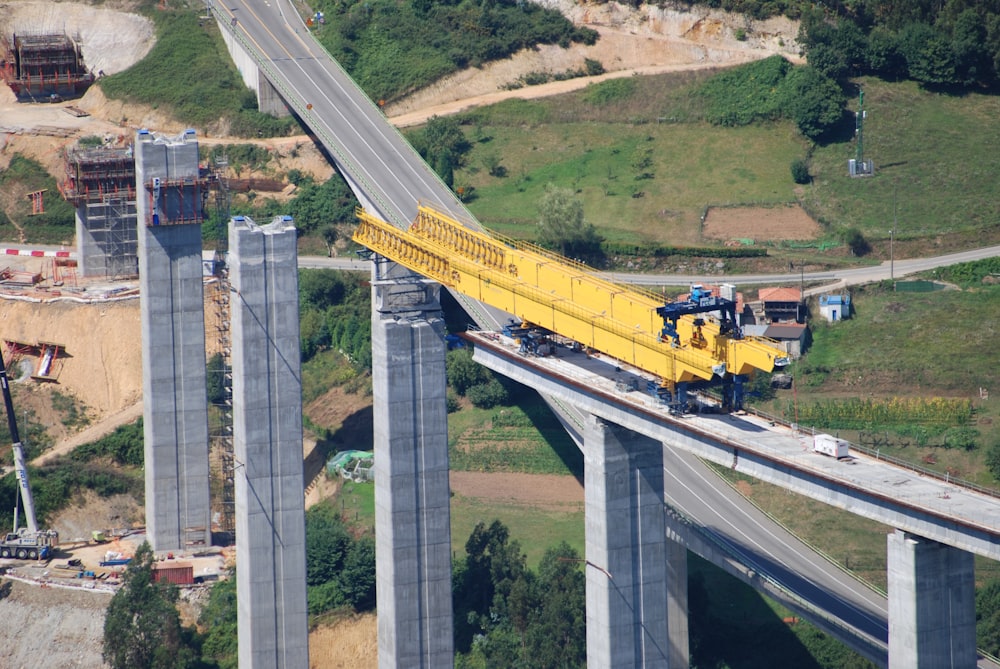 a yellow crane is on the side of a bridge