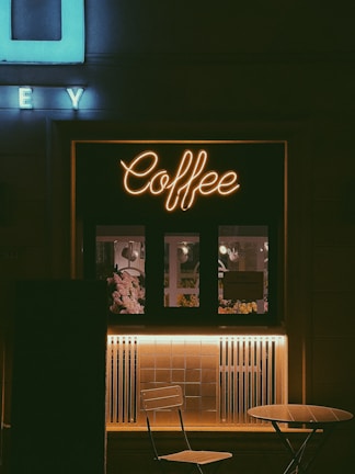 a coffee shop with a neon sign above it