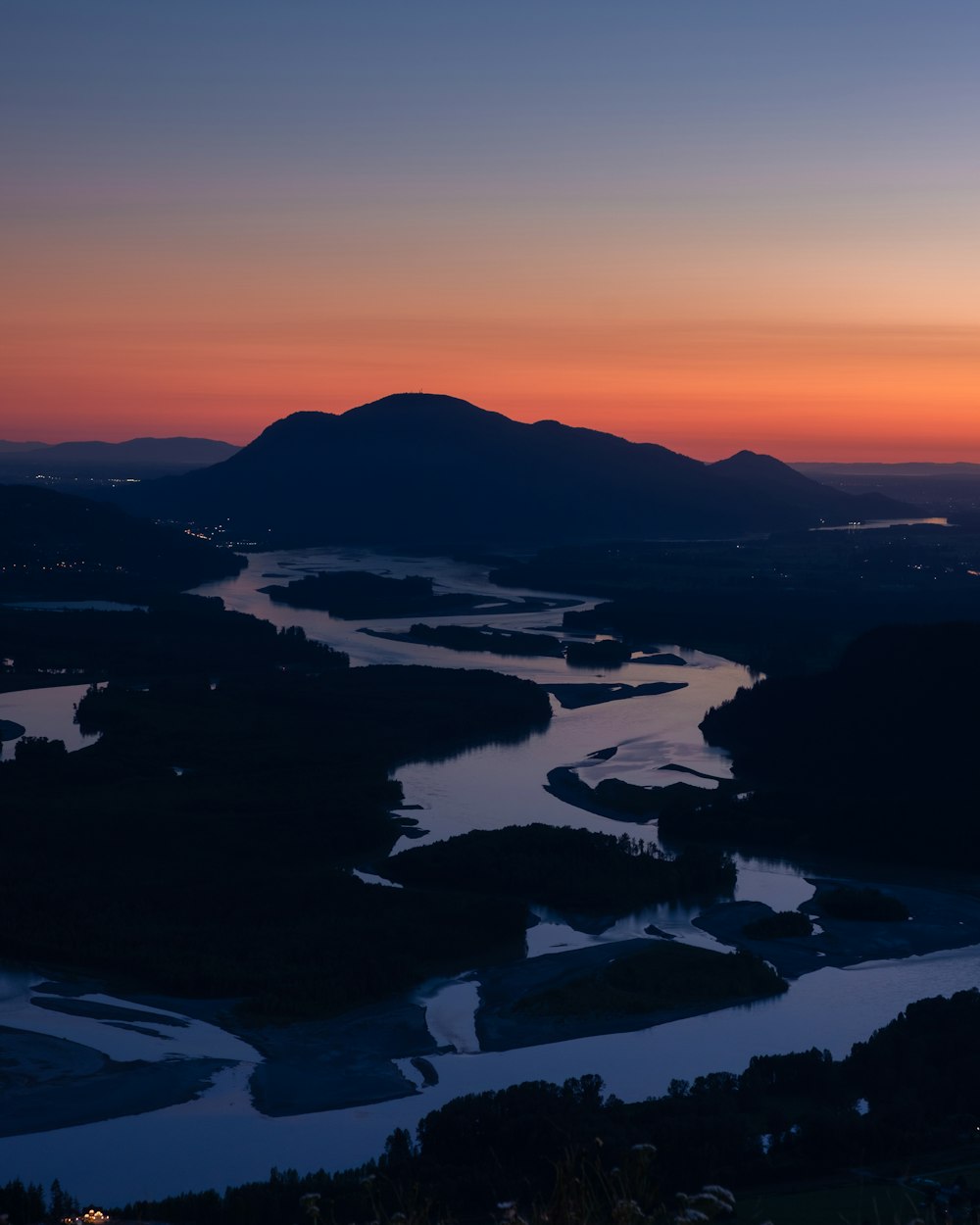 the sun is setting over a river and mountains