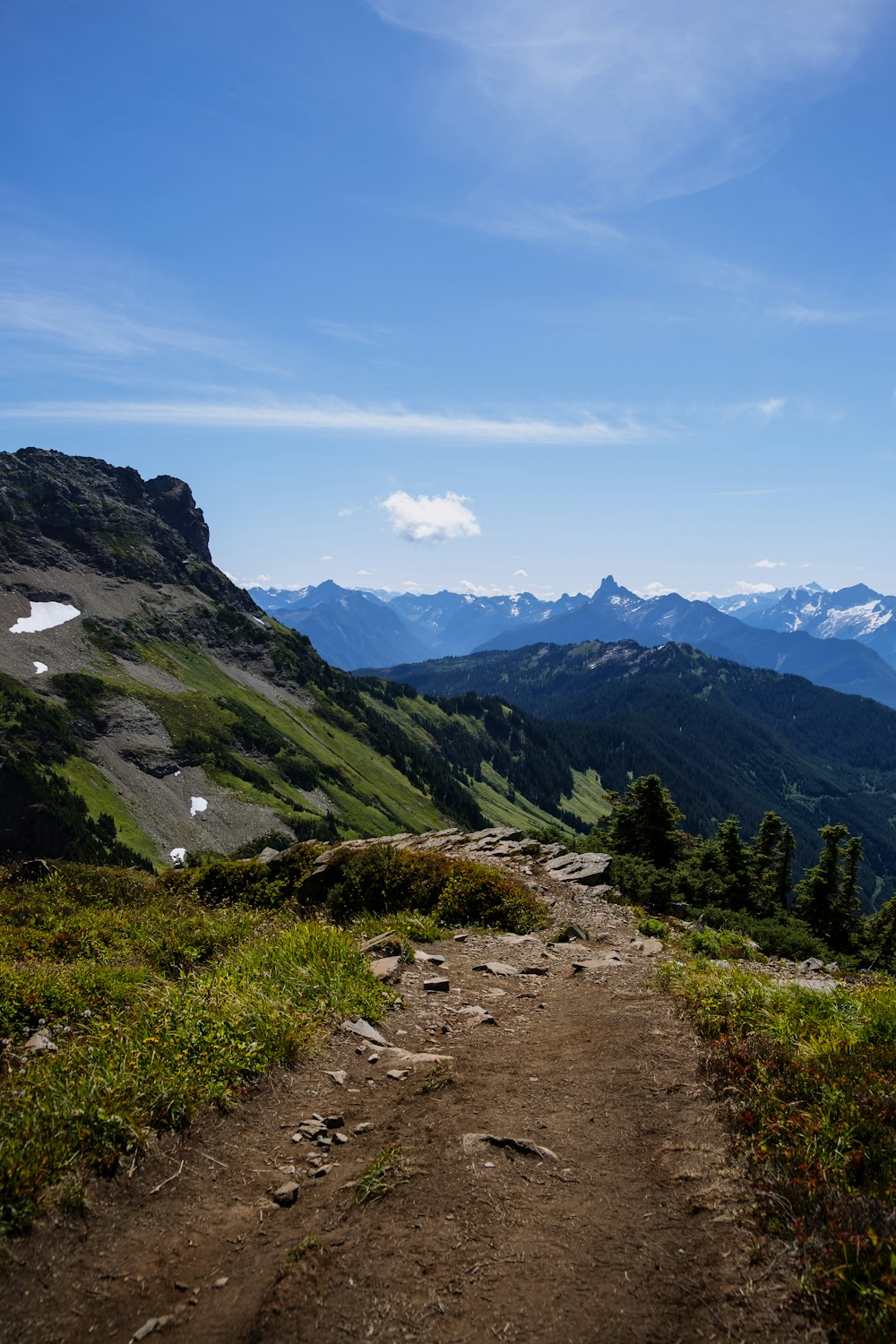 a dirt path going up a mountain with mountains in the background