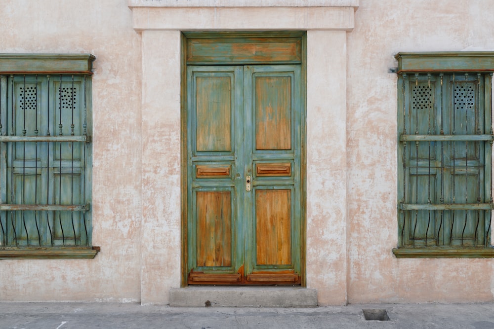 an old building with two green doors and two windows