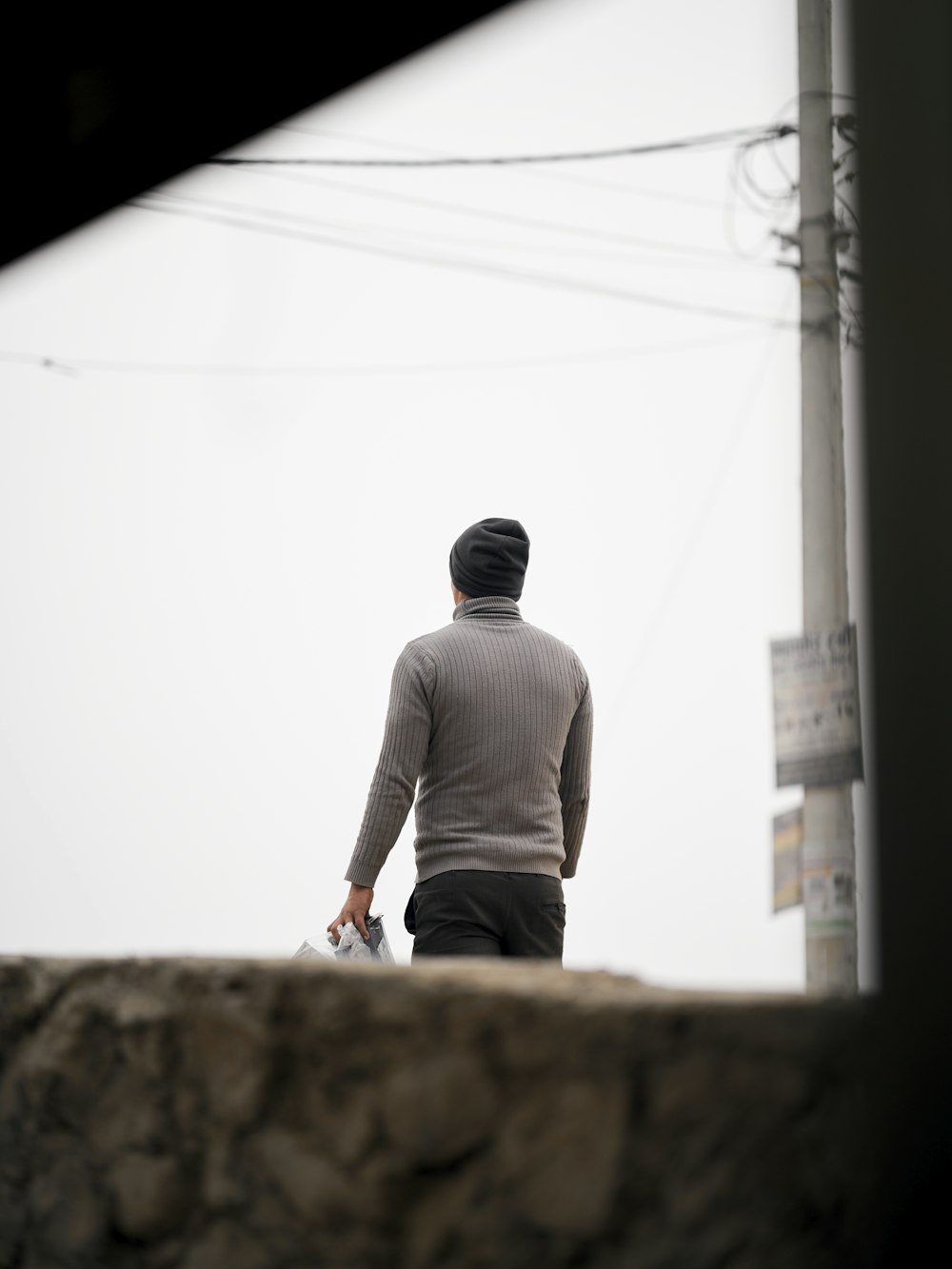 a man walking down a street next to power lines