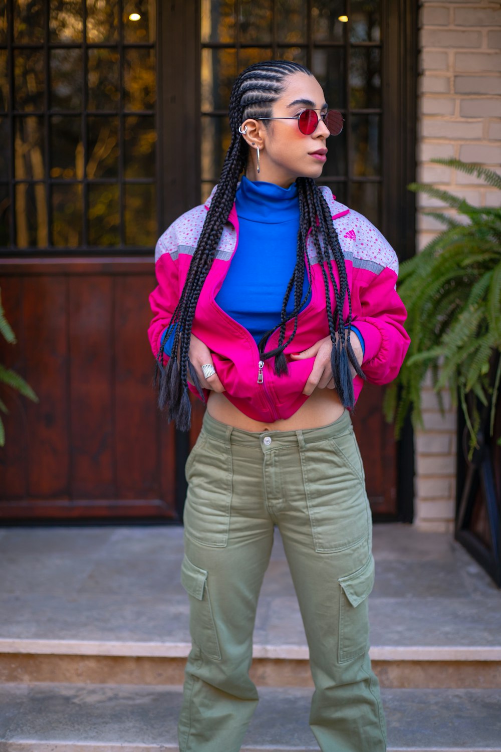 a woman with dreadlocks wearing a pink jacket and green pants