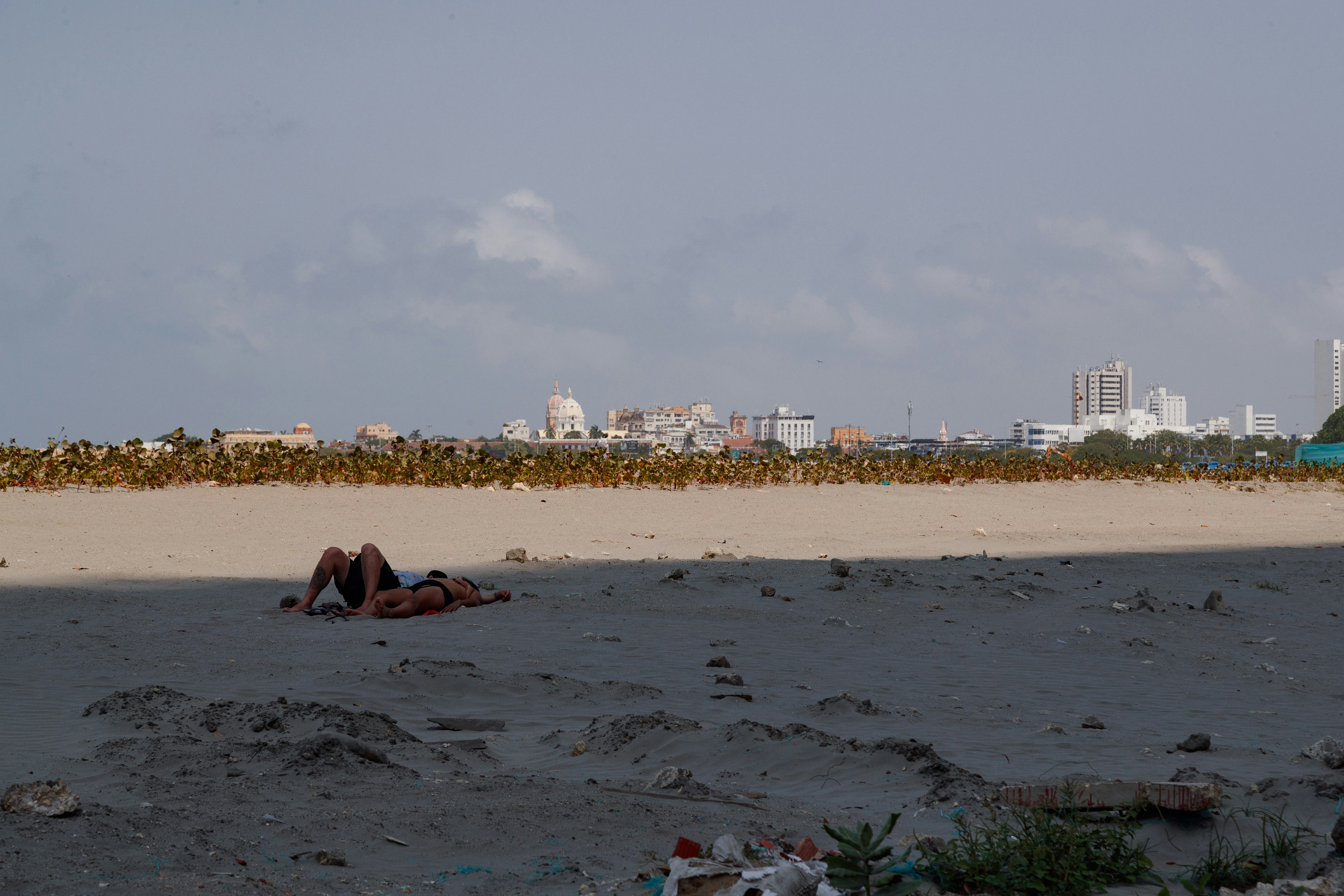 a couple of people laying on top of a sandy beach
