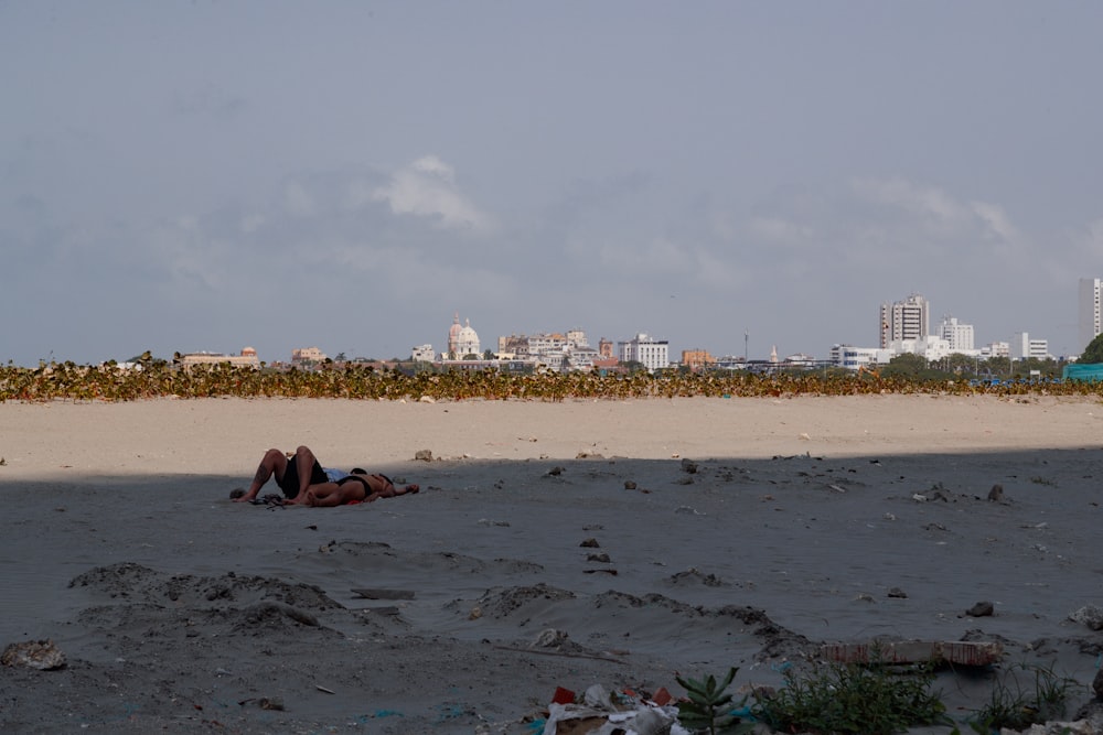 um casal de pessoas deitadas em cima de uma praia de areia