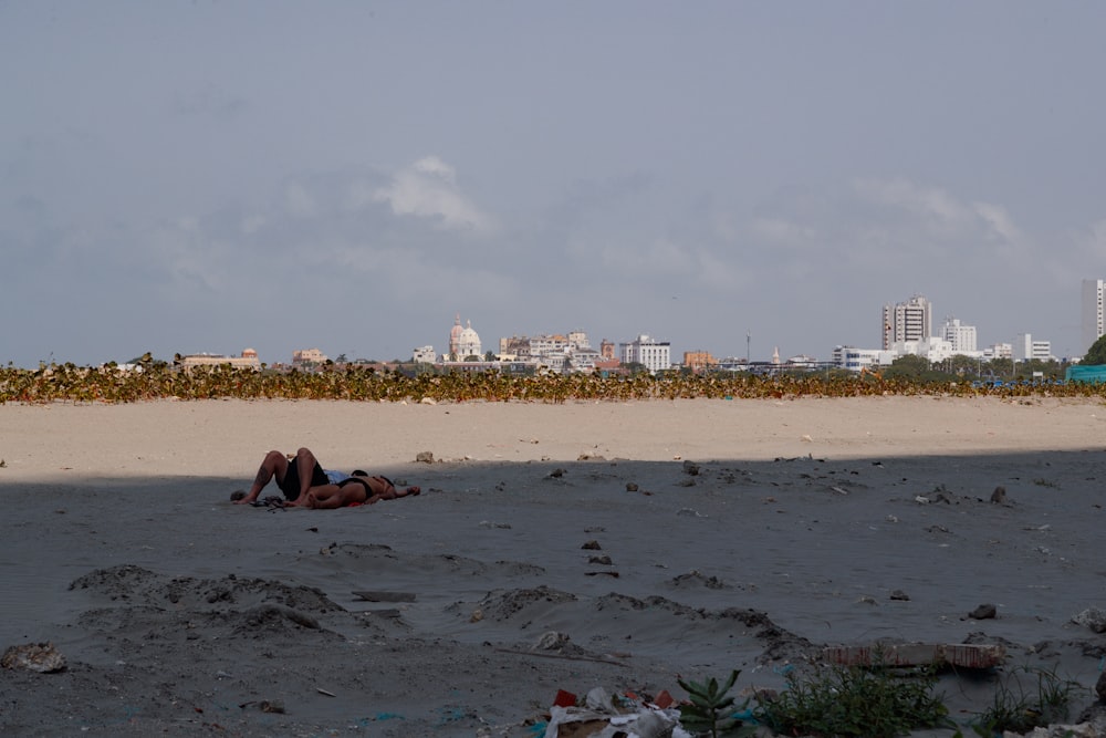 a couple of people laying on top of a sandy beach