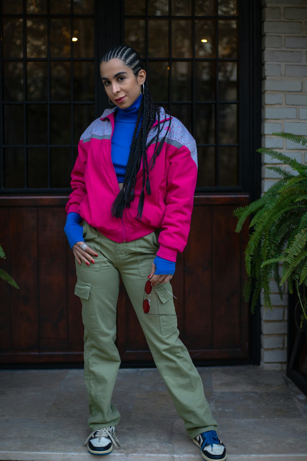 a woman standing in front of a door wearing a pink and blue jacket