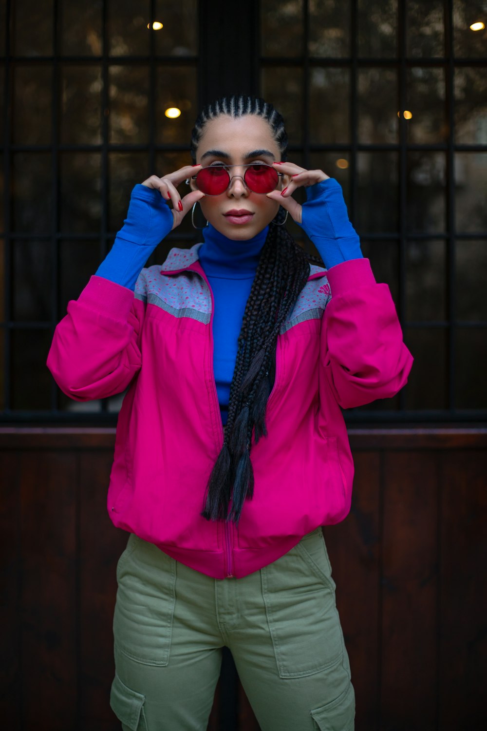a woman wearing a pink jacket and green pants