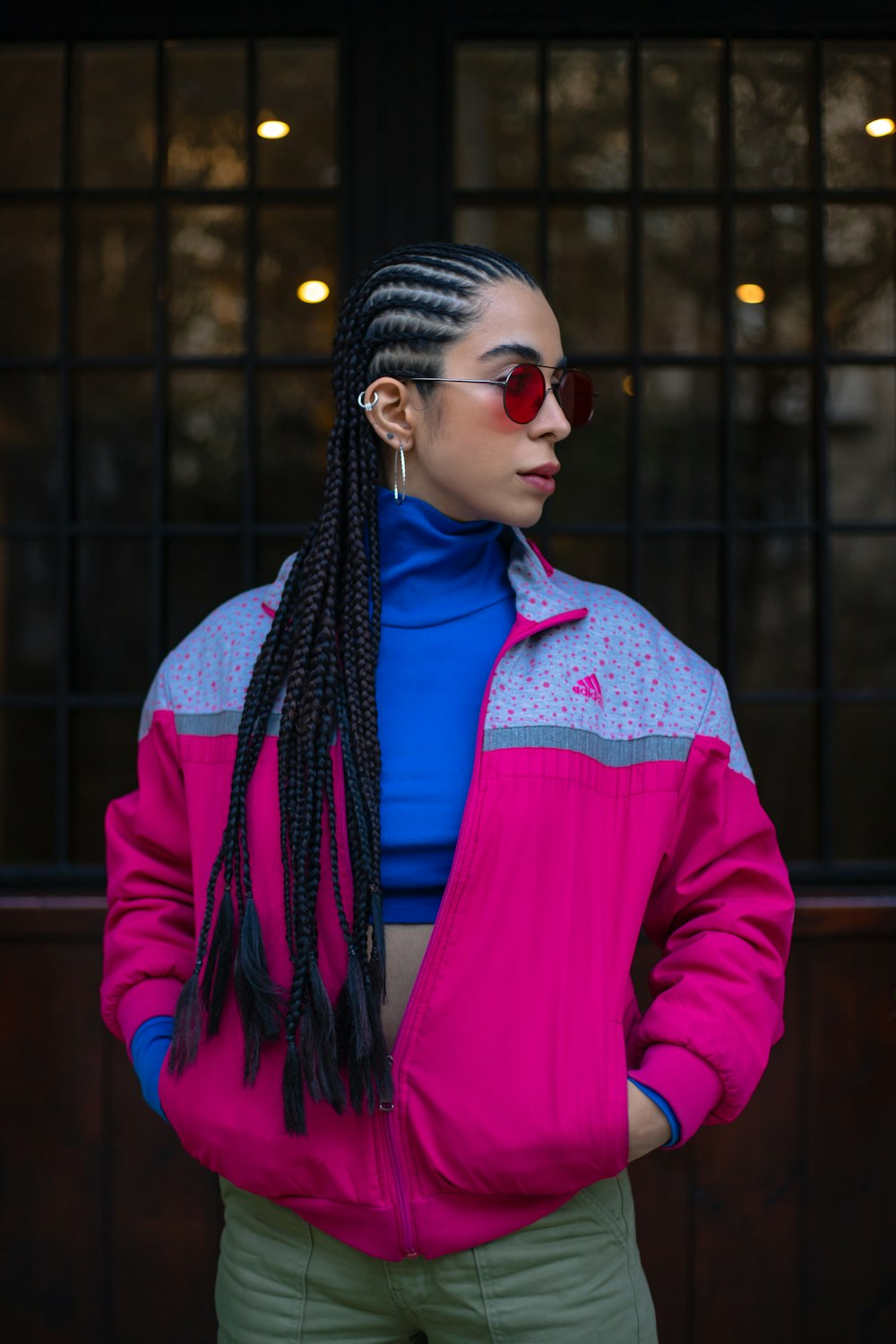 a woman wearing a pink jacket and green pants