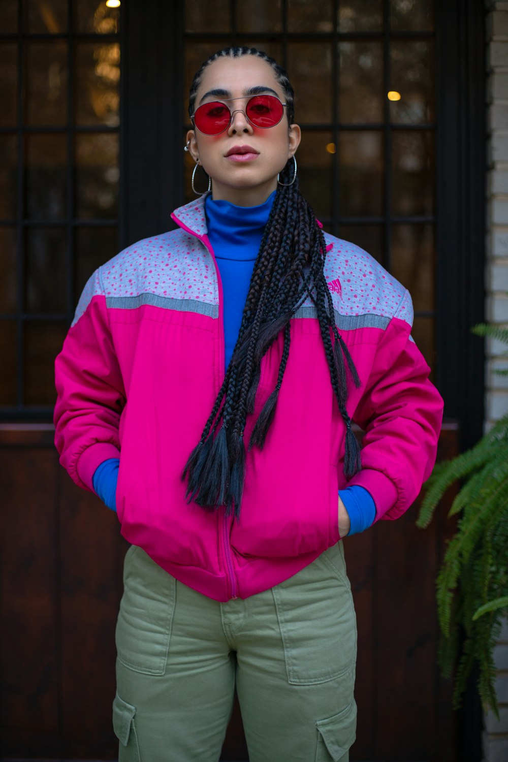 a woman wearing a pink jacket and green pants