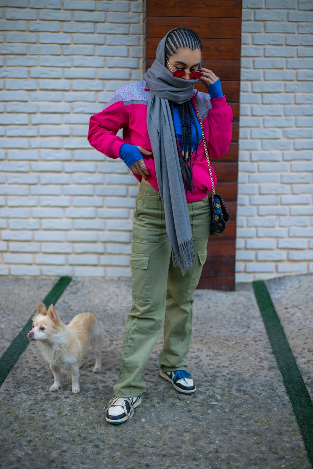 a woman in a pink jacket and scarf standing next to a dog