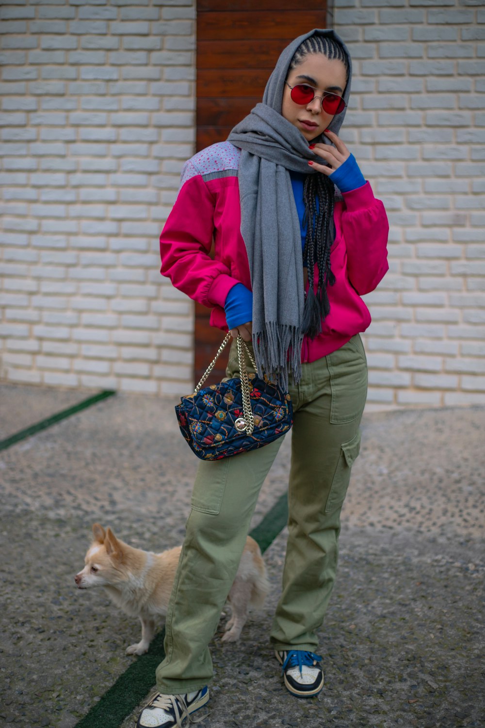 a woman in a pink jacket and scarf standing next to a dog