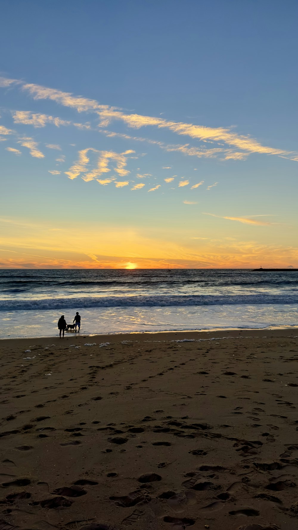 a couple of people standing on top of a sandy beach