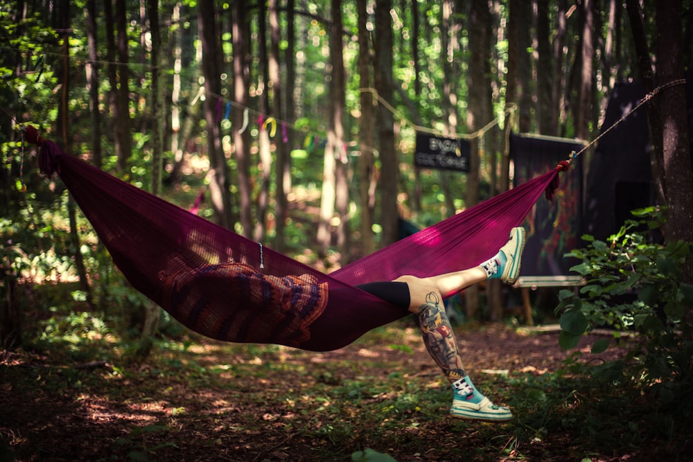 a woman laying in a hammock in the woods