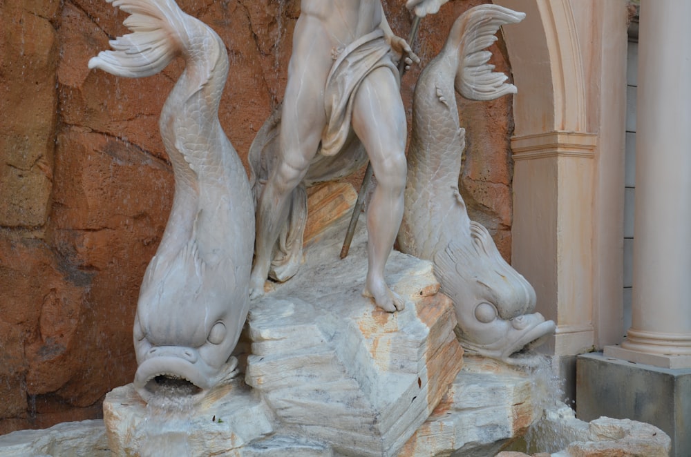 a statue of a man holding two fish