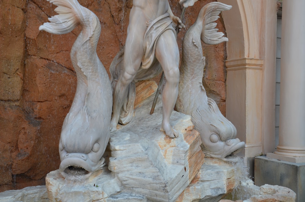 una estatua de un hombre sosteniendo dos peces