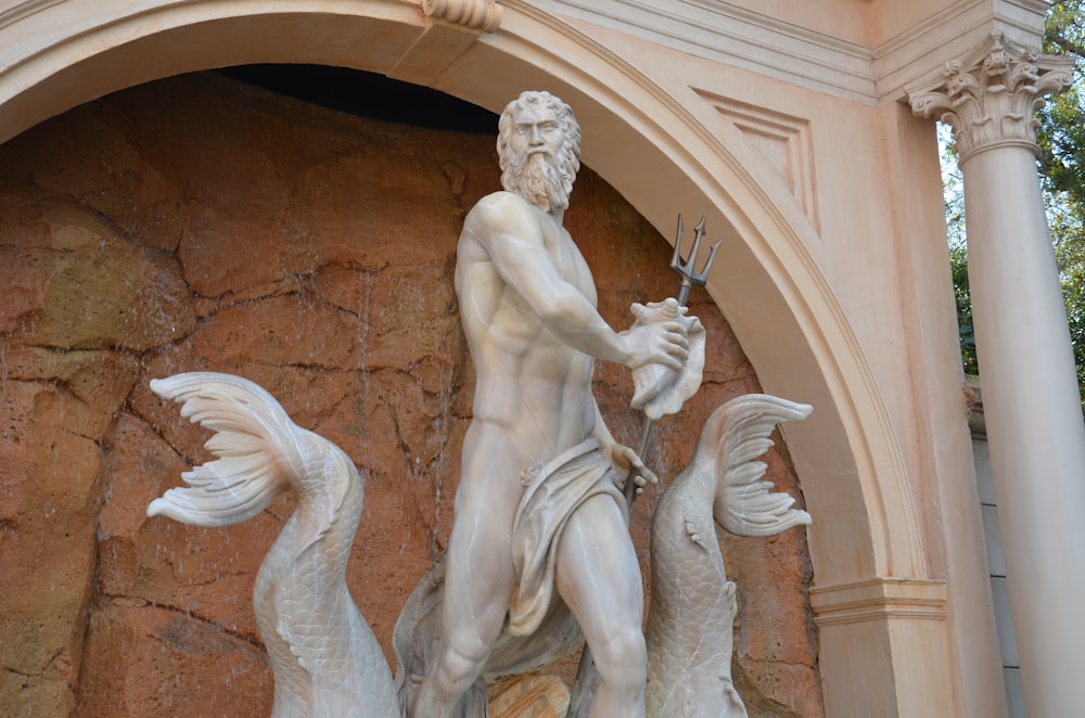 una estatua de un hombre sosteniendo una espada frente a un edificio