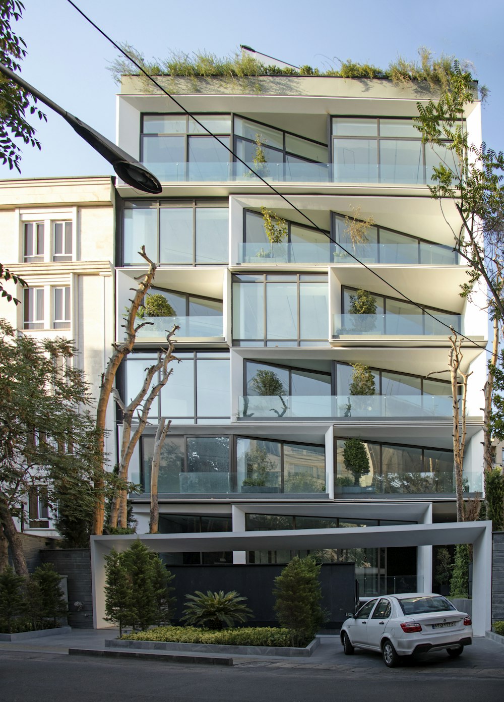 a white car parked in front of a tall building