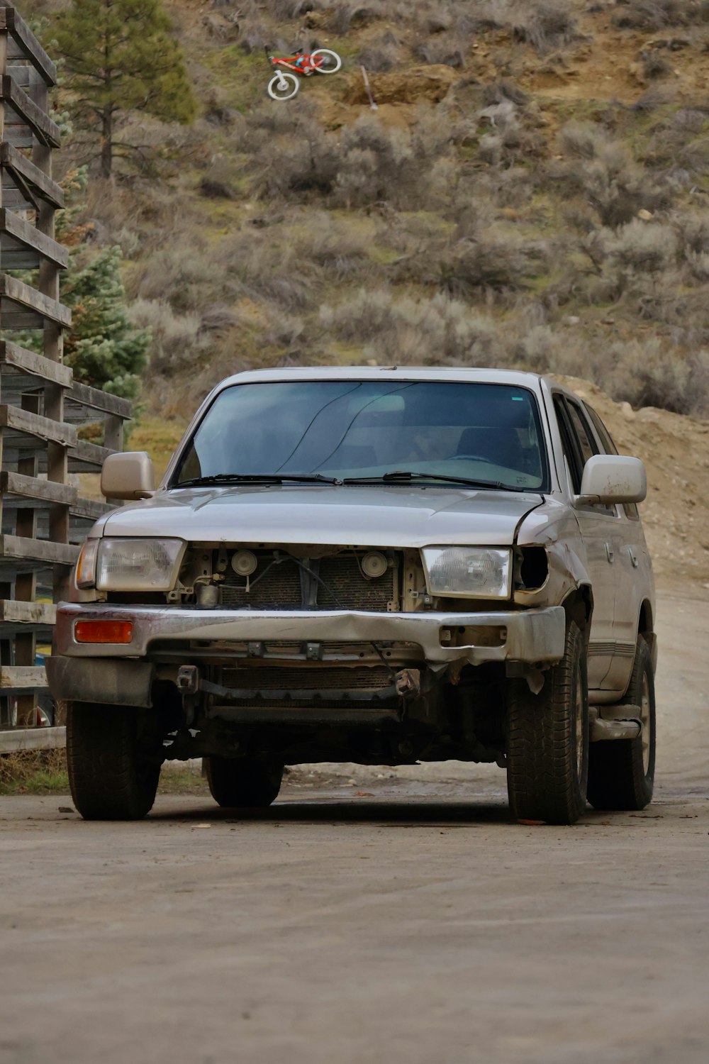 a silver truck driving down a dirt road