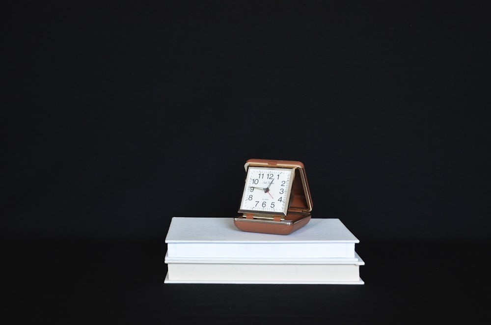 a clock sitting on top of a stack of books