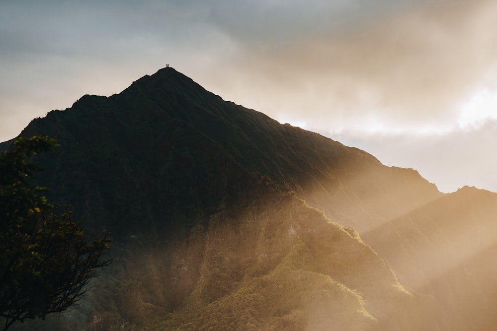 the sun is shining through the clouds over a mountain