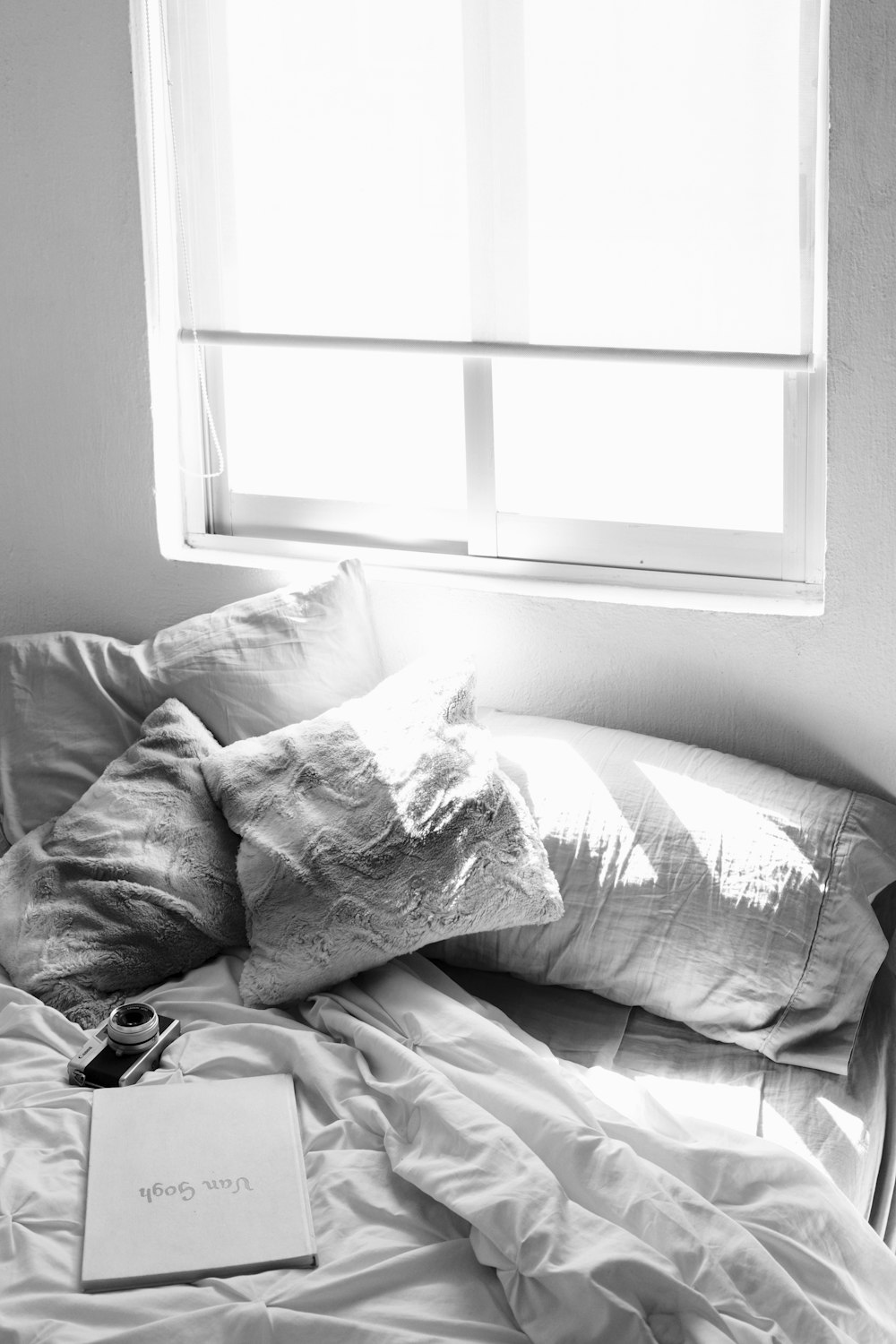 a bed with a book on top of it next to a window