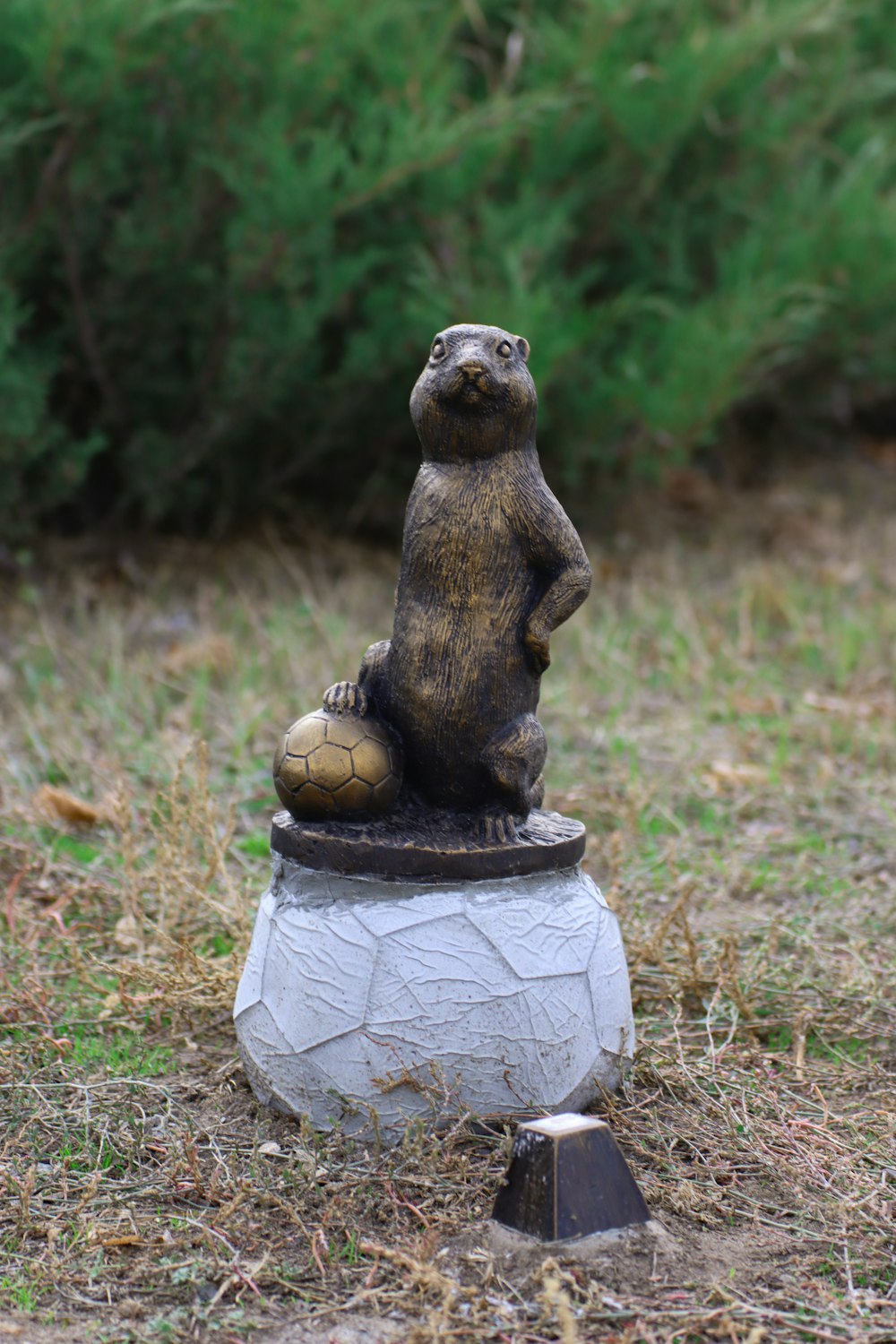 una estatua de un oso sentado encima de una pelota de fútbol