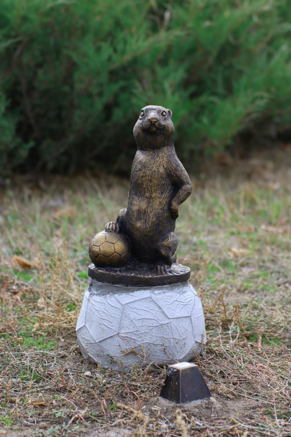 una statua di un orso seduto in cima a un pallone da calcio