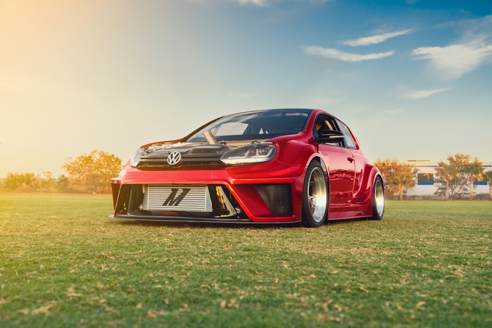 a red car parked on top of a lush green field