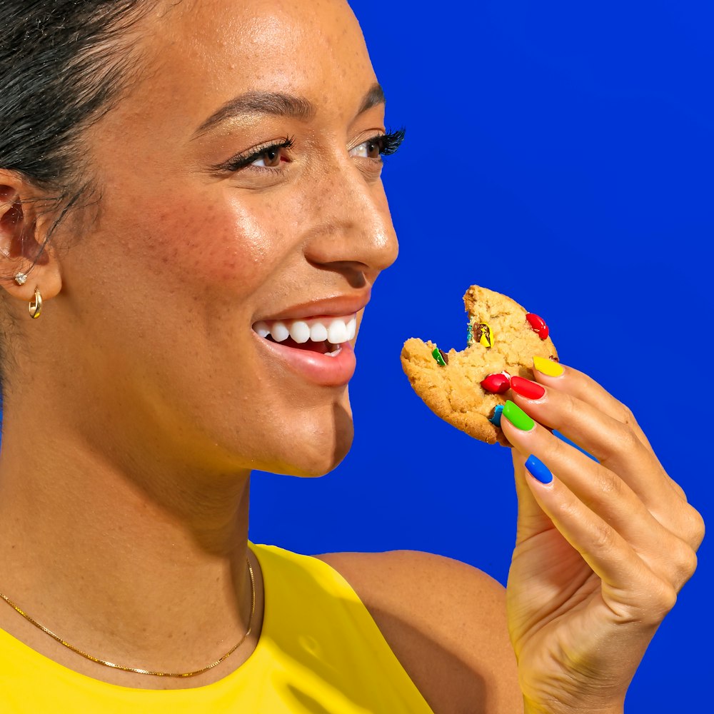 a woman eating a cookie with candy on it