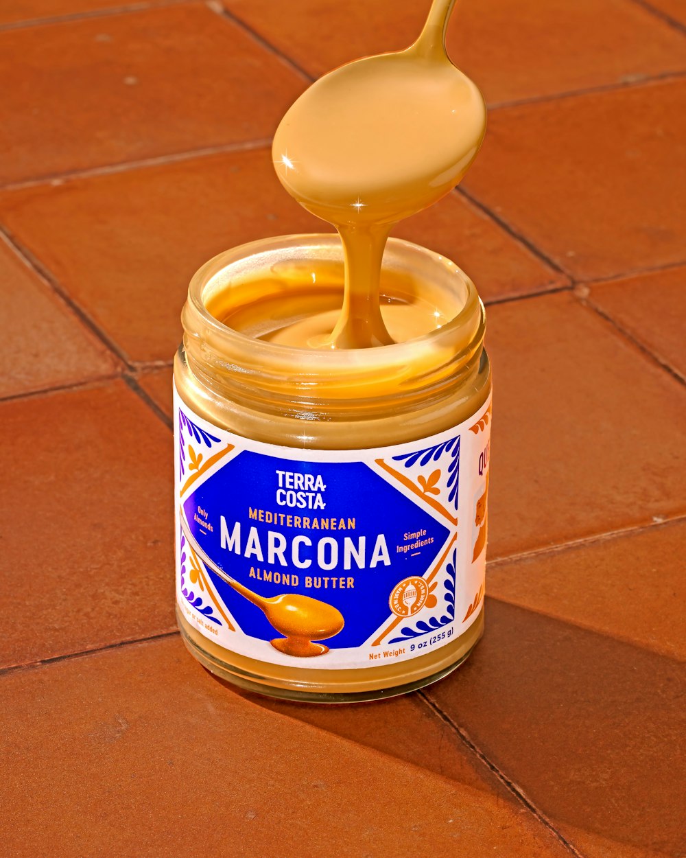 a jar of marcona sitting on a tiled floor