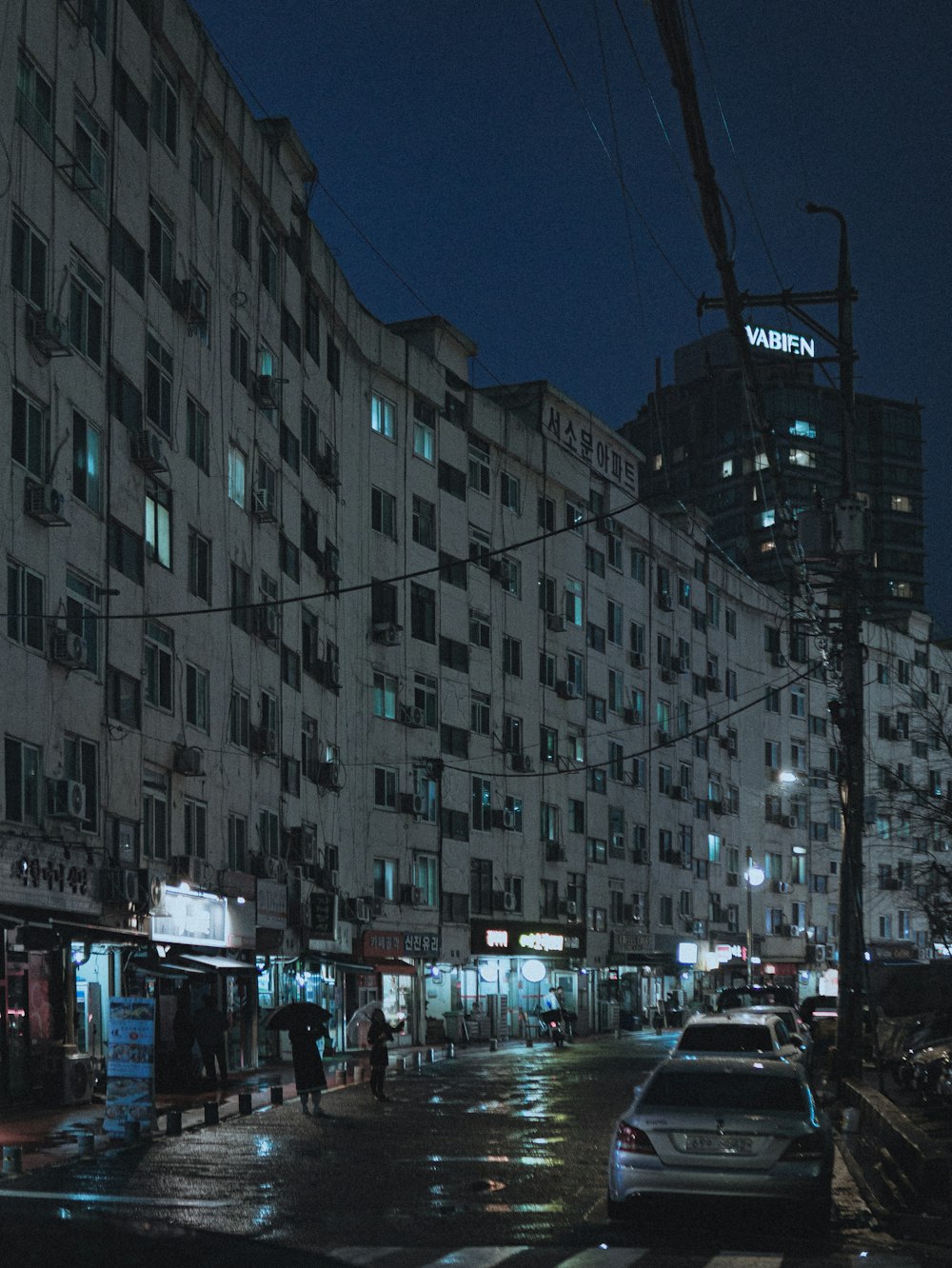 a city street at night with cars parked on the side of the road