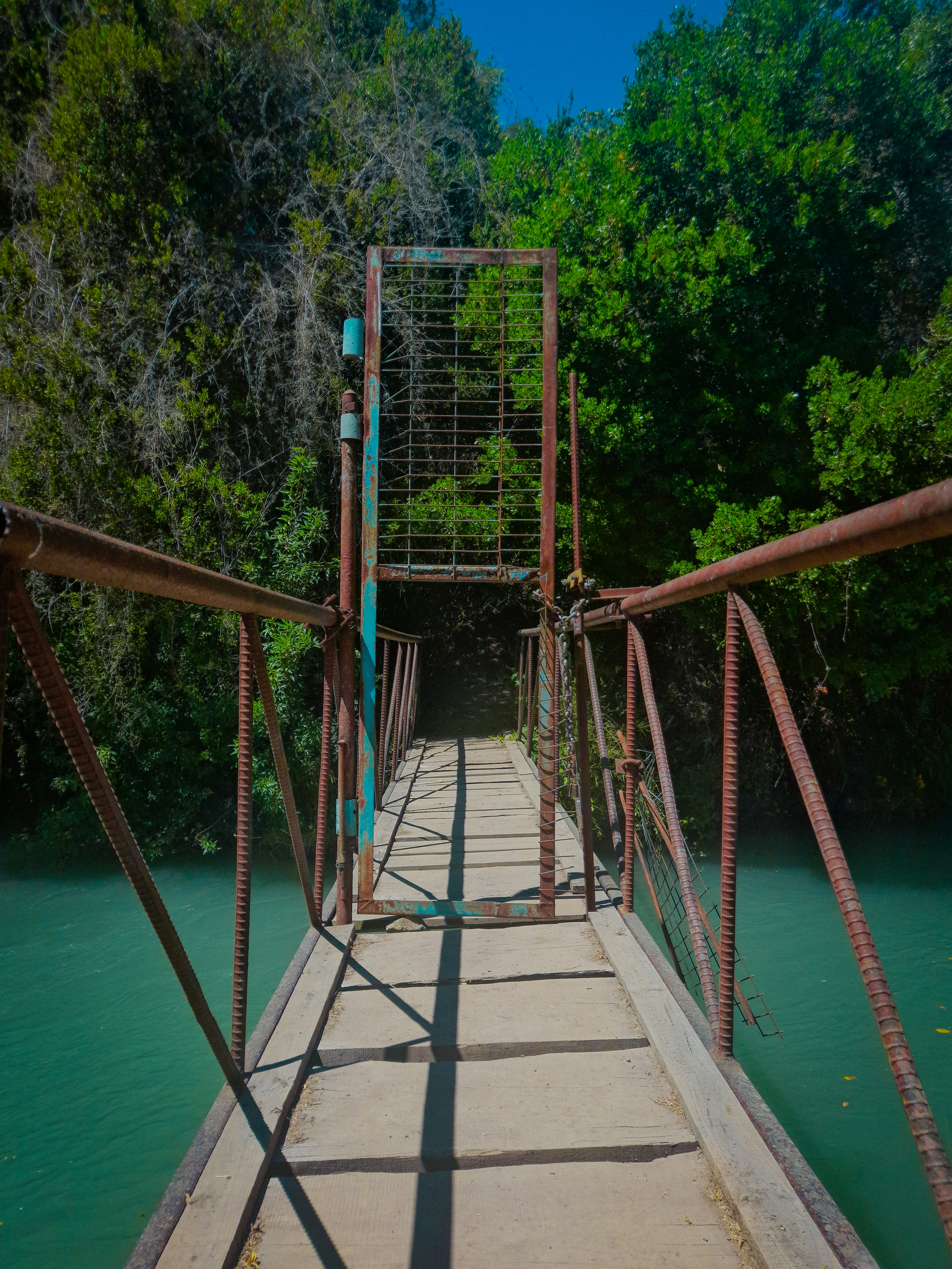 a metal bridge over a river surrounded by trees