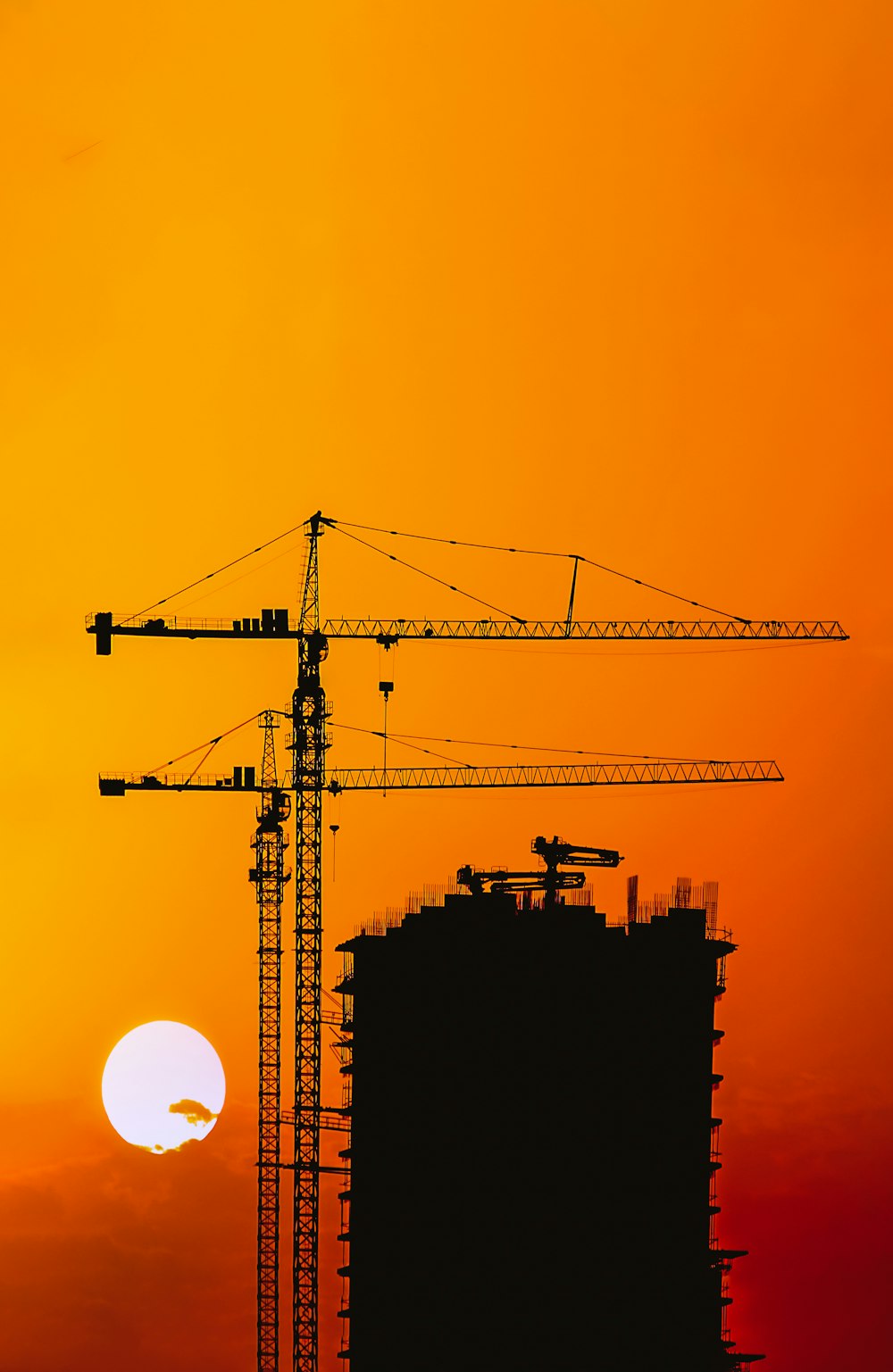 the sun is setting behind a building under construction