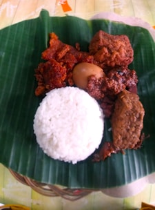 a plate of food on a banana leaf on a table
