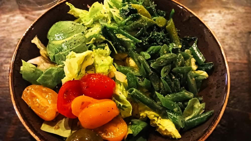 a brown bowl filled with vegetables on top of a wooden table