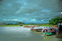 a group of people standing on the side of a river next to boats